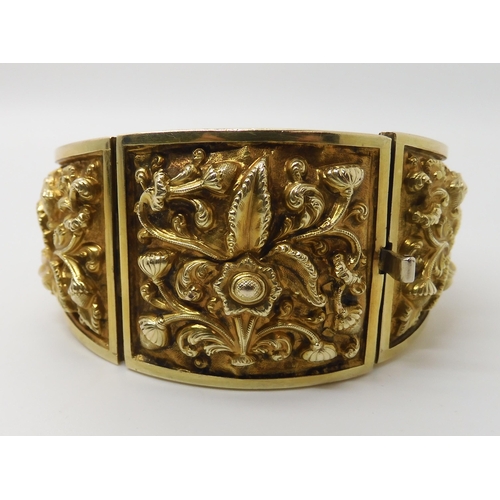 522 - A GILDED WHITE METAL REPOUSSE INDIAN BANGLE