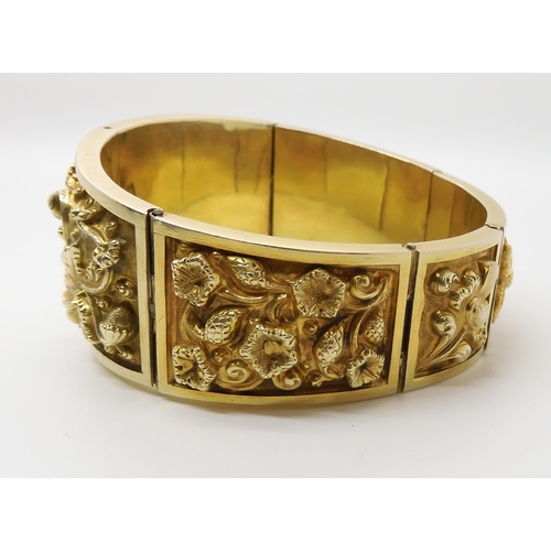 522 - A GILDED WHITE METAL REPOUSSE INDIAN BANGLE