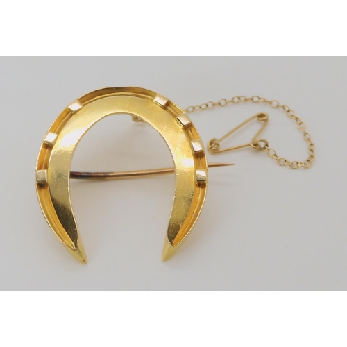 529 - A BRIGHT YELLOW METAL HORSESHOE BROOCH