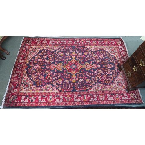 44 - A dark blue ground Persian rug with red central medallion, cream spandrels and red floral borders, 2... 