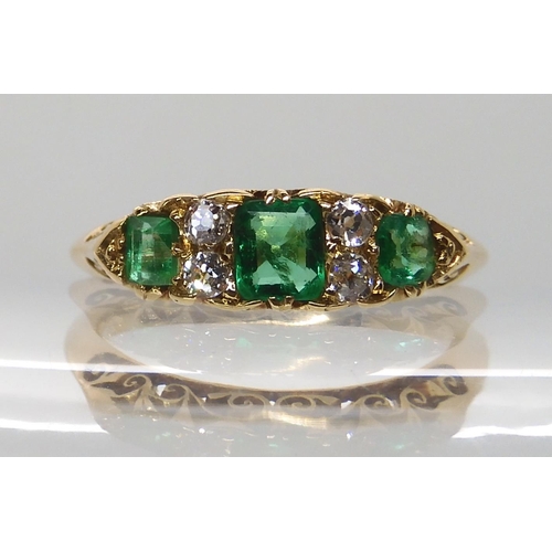 638 - AN 18CT GOLD EMERALD AND DIAMOND RING IN A SCROLLED MOUNT