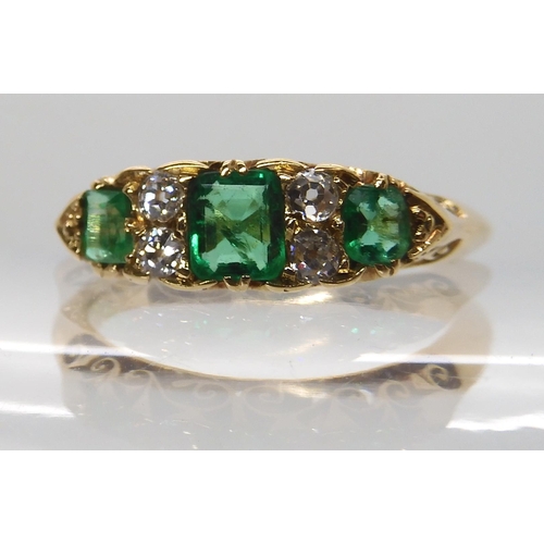 638 - AN 18CT GOLD EMERALD AND DIAMOND RING IN A SCROLLED MOUNT