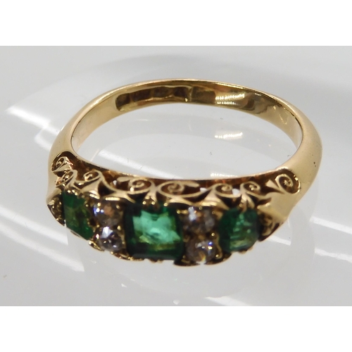 638 - AN 18CT GOLD EMERALD AND DIAMOND RING IN A SCROLLED MOUNT