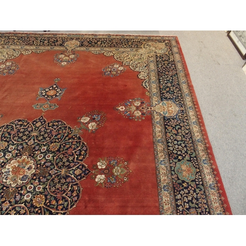 90 - A RED GROUND KESHAN RUG WITH BLUE CENTRAL MEDALLION AND MATCHING BORDER