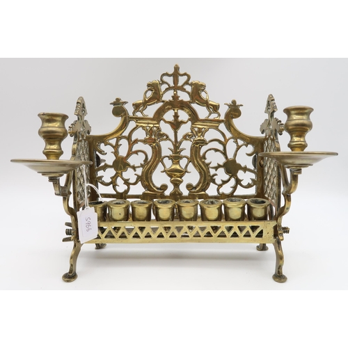 590 - A DUTCH JEWISH BRASS MINORA cast with a scrolling backplate above the row of candle nozzles, 25cm hi... 