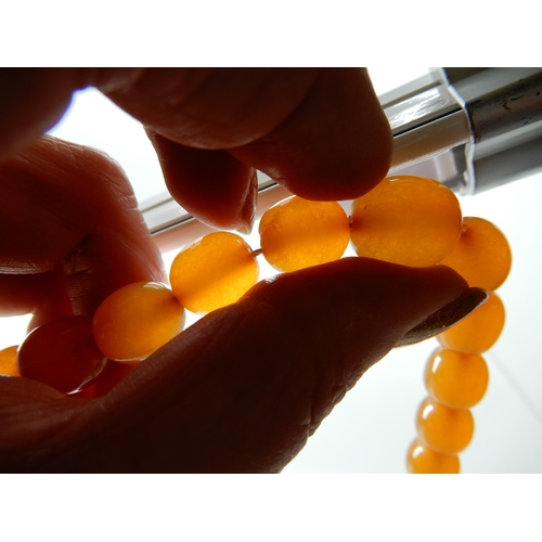 549 - A STRING OF AMBER COLOURED BEADS