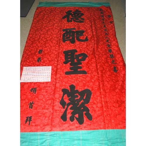 127 - A CHINESE SILK BANNER IN RED AND BLACK WITH CALLIGRAPHY