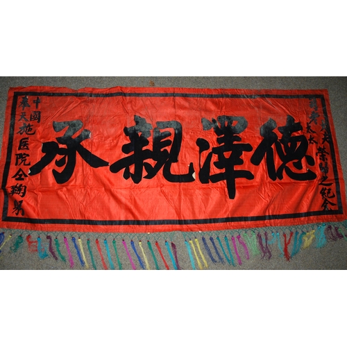 127 - A CHINESE SILK BANNER IN RED AND BLACK WITH CALLIGRAPHY