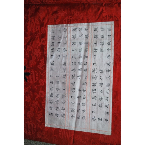 127 - A CHINESE SILK BANNER IN RED AND BLACK WITH CALLIGRAPHY