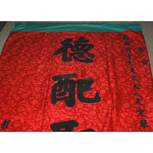 127 - A CHINESE SILK BANNER IN RED AND BLACK WITH CALLIGRAPHY