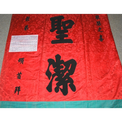 127 - A CHINESE SILK BANNER IN RED AND BLACK WITH CALLIGRAPHY