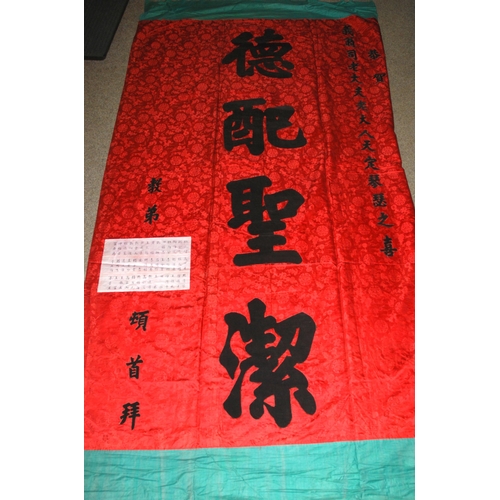 127 - A CHINESE SILK BANNER IN RED AND BLACK WITH CALLIGRAPHY