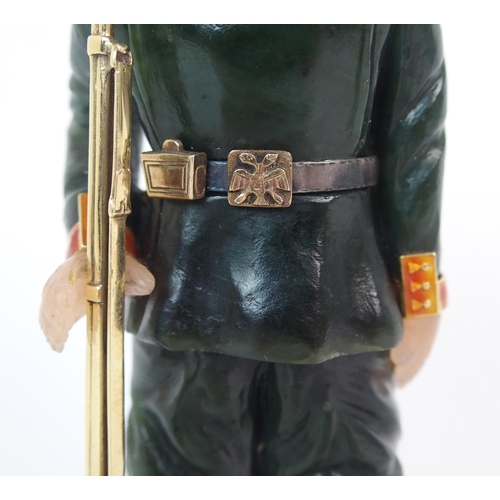 325 - A late 20th Century copy of a Faberge hard stone figure of a Cossack with yellow-metal rifle