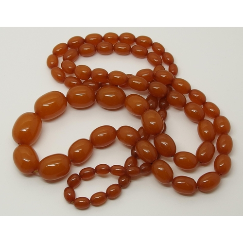 627 - A long string of amber coloured beads