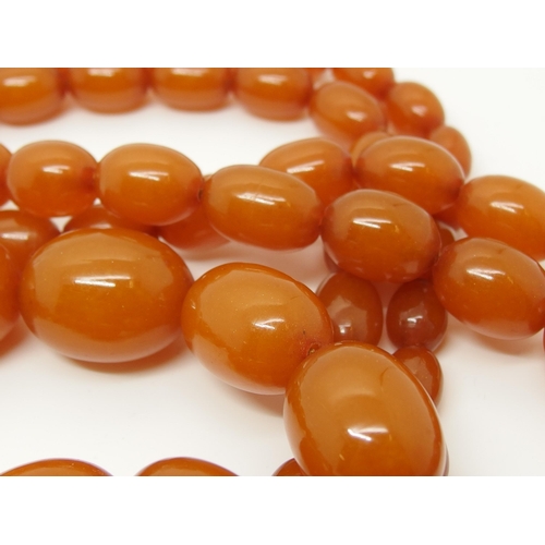 627 - A long string of amber coloured beads