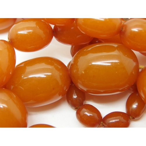 627 - A long string of amber coloured beads