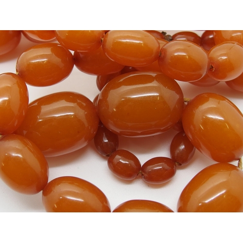 627 - A long string of amber coloured beads