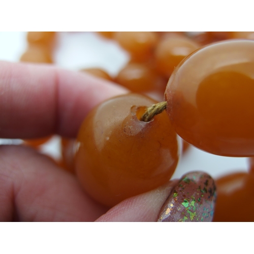 627 - A long string of amber coloured beads