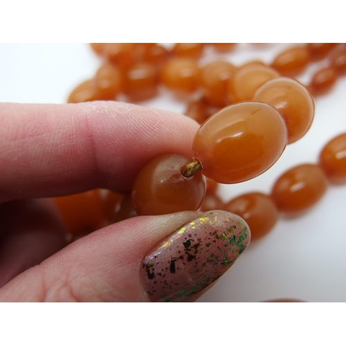 627 - A long string of amber coloured beads