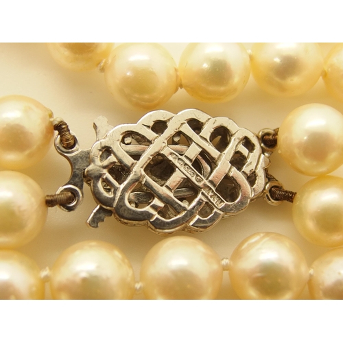 725 - A double string of baroque pearls with a 9ct diamond set clasp