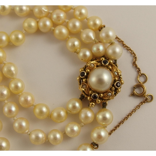 681 - A triple string of pearls with a garnet and pearl clasp