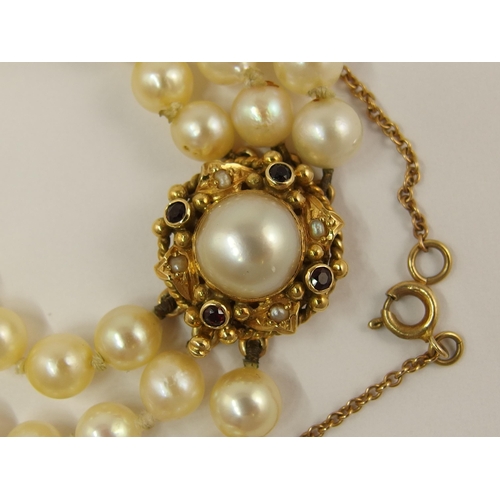 681 - A triple string of pearls with a garnet and pearl clasp