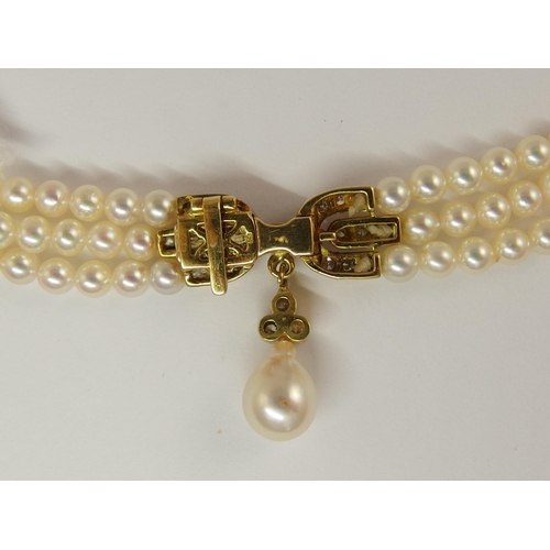 695 - A triple string of pearls with a diamond clasp