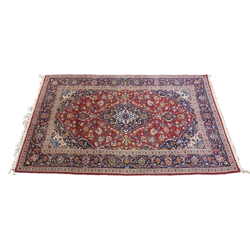 866 - A red ground and woven Persian Kashan rug