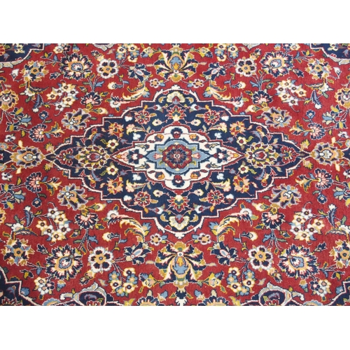 866 - A red ground and woven Persian Kashan rug