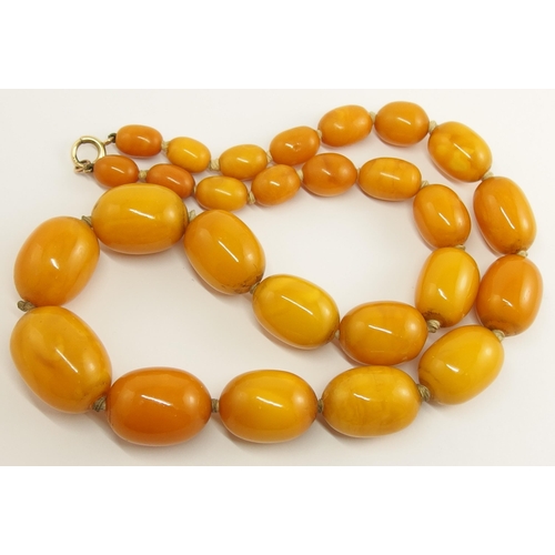 703 - A string of orange amber coloured beads