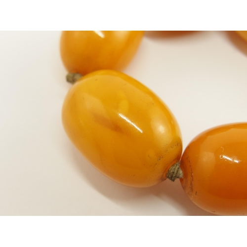 703 - A string of orange amber coloured beads