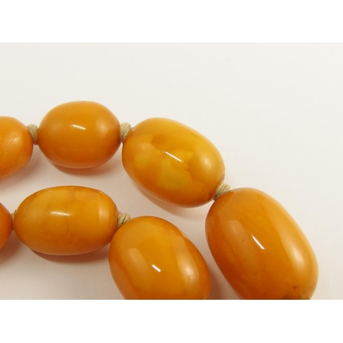 703 - A string of orange amber coloured beads