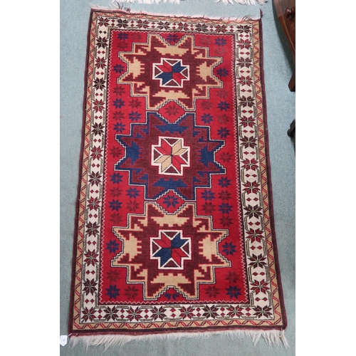 52 - A red ground geometric pattern rug with three medallions and cream borders, 182cm high x 104cm wide