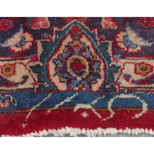 132 - A RED GROUND KESHAN RUGwith blue central medallion, matching spandrels and borders, signature to one... 