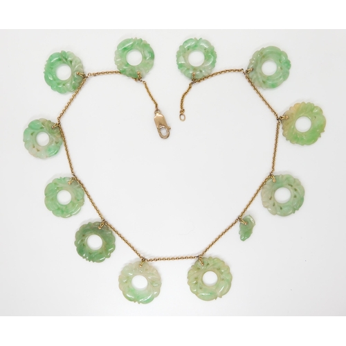 696 - A CHINESE GREEN HARDSTONE NECKLACEeach rondel is carved with foliage, (one is af) and attached to a ... 