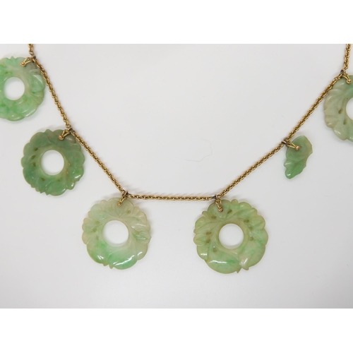 696 - A CHINESE GREEN HARDSTONE NECKLACEeach rondel is carved with foliage, (one is af) and attached to a ... 