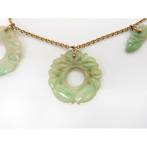 696 - A CHINESE GREEN HARDSTONE NECKLACEeach rondel is carved with foliage, (one is af) and attached to a ... 