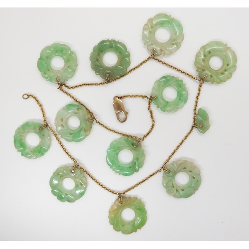 696 - A CHINESE GREEN HARDSTONE NECKLACEeach rondel is carved with foliage, (one is af) and attached to a ... 