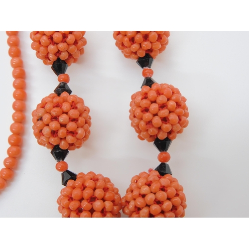 747 - CORAL STATEMENT BEADSa string of woven coral beads, with black glass beads and ribbon strap. Each wo... 