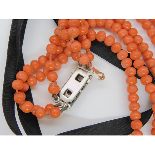 747 - CORAL STATEMENT BEADSa string of woven coral beads, with black glass beads and ribbon strap. Each wo... 