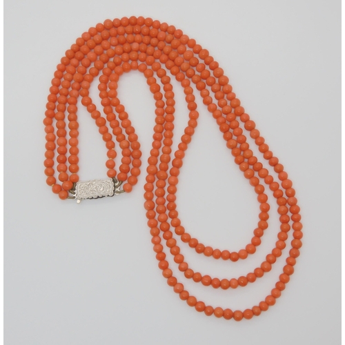 756 - A TRIPLE STRING OF CORAL BEADSall beads approx 5mm in diameter, shortest length 48cm, with a decorat... 