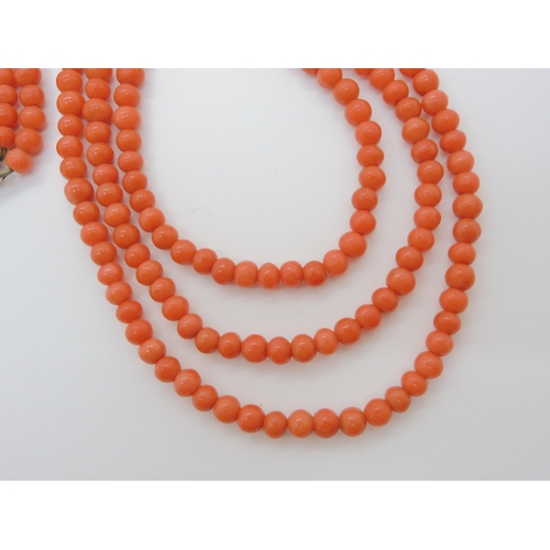 756 - A TRIPLE STRING OF CORAL BEADSall beads approx 5mm in diameter, shortest length 48cm, with a decorat... 