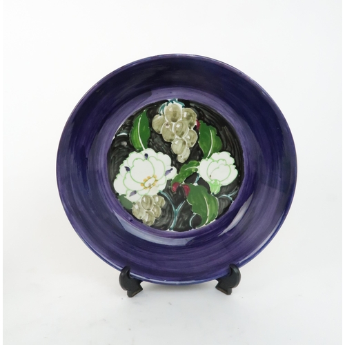 173 - AN ELIZABETH AMOUR FOR BOUGH POTTERY BOWLpainted with flowers and grapes on a black ground with a pu... 