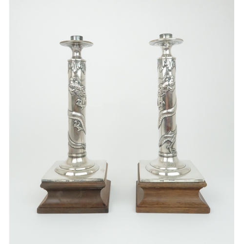 307 - A PAIR OF CHINESE SILVER CANDLESTICK LAMPScast with sinuous dragons, beneath acanthus leaf and above... 