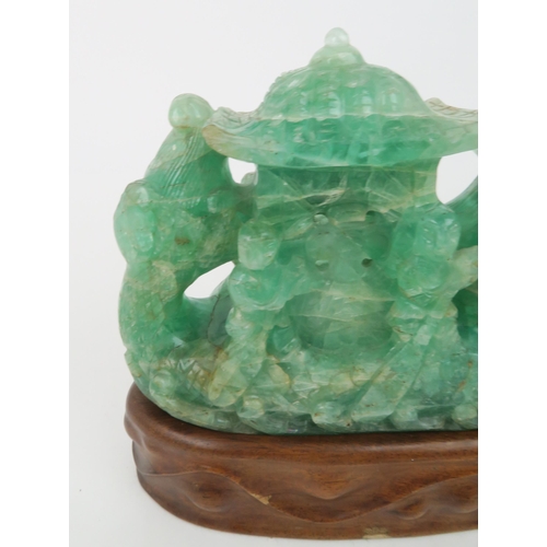 321 - A CHINESE GREEN FLUORSPAR LAMP CARVINGcarved as a dragon boat, seated on a carved hardwood base, 24c... 