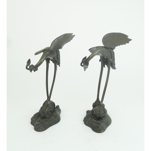 322 - A PAIR OF CHINESE BRONZE JOSS STICK HOLDERSeach cast as storks with lily pads and standing on waves ... 