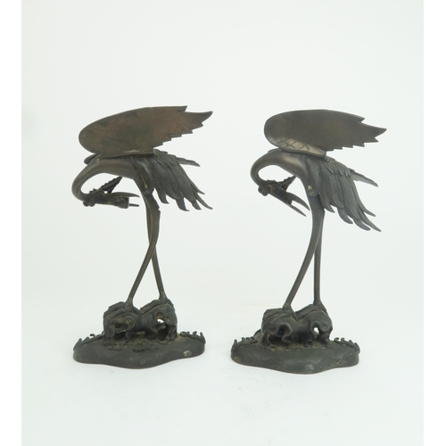 322 - A PAIR OF CHINESE BRONZE JOSS STICK HOLDERSeach cast as storks with lily pads and standing on waves ... 