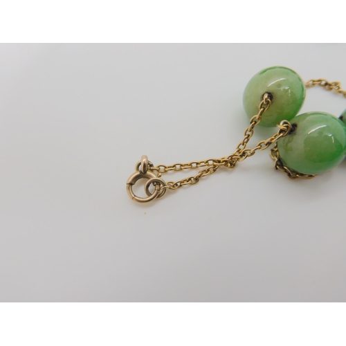 762 - A STRING OF CHINESE GREEN HARDSTONE BEADSlinked with yellow metal chains. each bead is 13.4mm, lengt... 