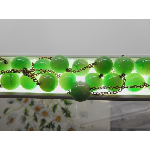 762 - A STRING OF CHINESE GREEN HARDSTONE BEADSlinked with yellow metal chains. each bead is 13.4mm, lengt... 