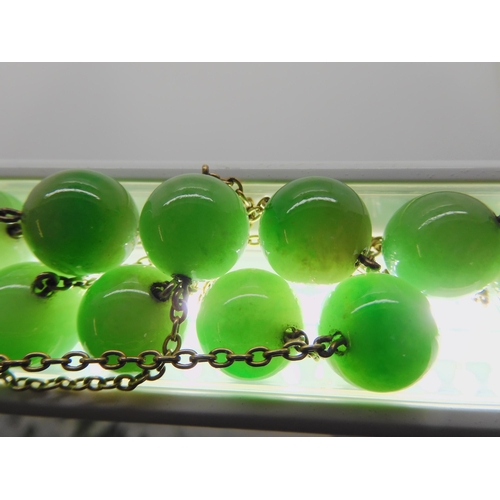 762 - A STRING OF CHINESE GREEN HARDSTONE BEADSlinked with yellow metal chains. each bead is 13.4mm, lengt... 